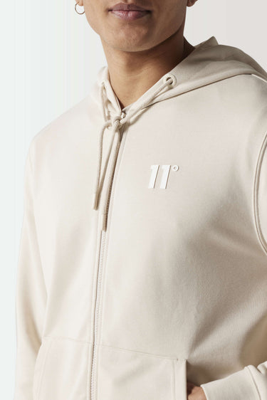 Light beige full-zip hoodie close-up with drawstring hood and chest logo