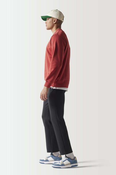 Red crewneck sweatshirt, side view with ribbed cuffs and small black chest logo