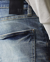 Mid-blue denim jeans waistband with black tab and belt loops