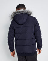 Men's dark puffer jacket back view with faux-fur hood and quilted panels