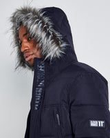 Dark puffer jacket detail: faux-fur hood trim and sleeve logo patch