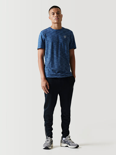 Black athletic pants with white logo on thigh and tapered legs.