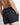 Close-up of black swim shorts: elastic waistband, zipper pocket, logo