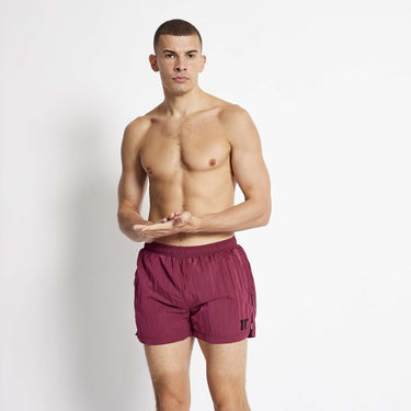 Maroon micro taped swim shorts with elastic waistband and side taping.