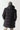 Black longline puffer jacket back view with attached hood and quilted panels