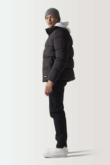 Black panel puffer jacket shown from side with full-zip front and quilted insulation
