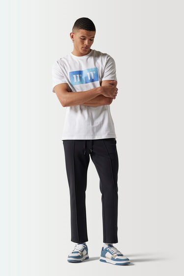 Black track pants on model, tapered leg and elastic waistband