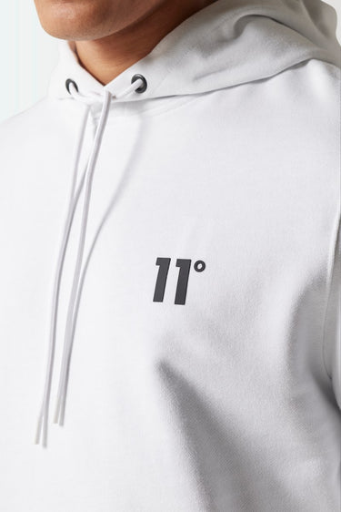 White hoodie close-up with '11°' emblem and lace-up hood drawstrings.