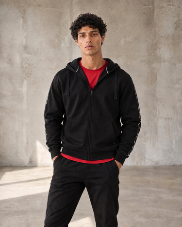 Black full-zip hoodie with hood, front zipper, and side pockets; red lining at collar