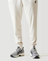 Stone beige joggers close-up: tapered legs, cuffed hem, side logo