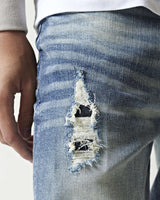 Mid-blue denim jeans with stitched distressed rip on back leg