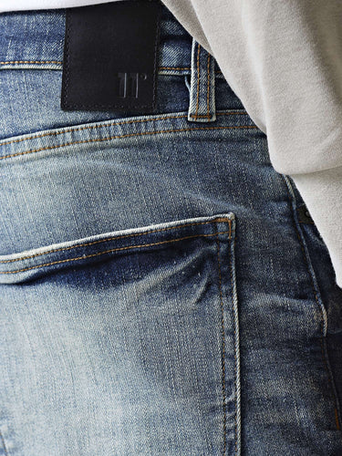 Mid-blue denim jeans waistband with black tab and belt loops