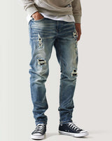 Mid-blue ripped jeans with multiple distressed patches and frayed cuffs