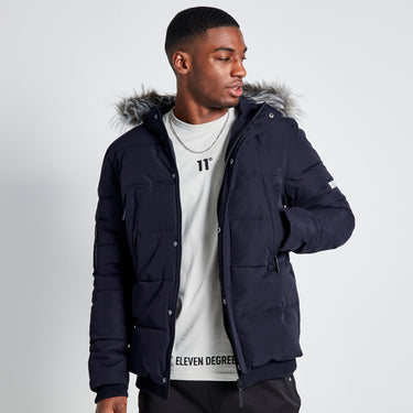 Men's dark puffer jacket with faux-fur hood trim and chest logo patch