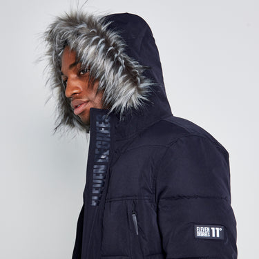 Dark puffer jacket detail: faux-fur hood trim and sleeve logo patch