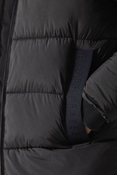 Black puffer jacket fabric close-up with vertical logo-embossed label