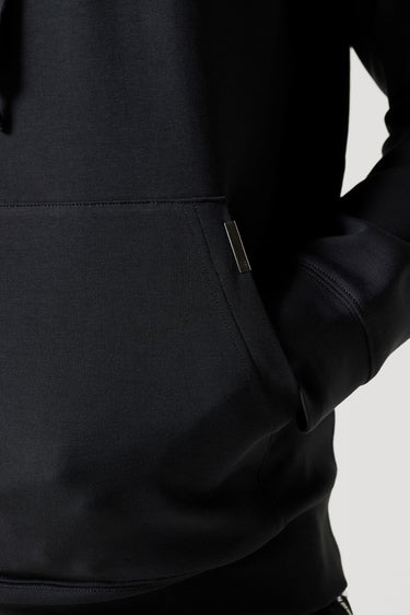 Black hoodie kangaroo pocket with metal drawstring ends and stitched hem