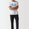 Black track pants on model, tapered leg and elastic waistband
