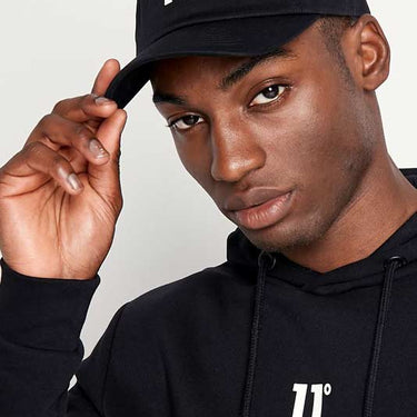 Black baseball cap with white 11° logo on front, close-up