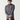 A man wearing a dark gray heathered long-sleeve quarter-zip athletic pullover with a white logo on the left chest, paired with a black baseball cap and black pants, photographed against a light gray studio background.